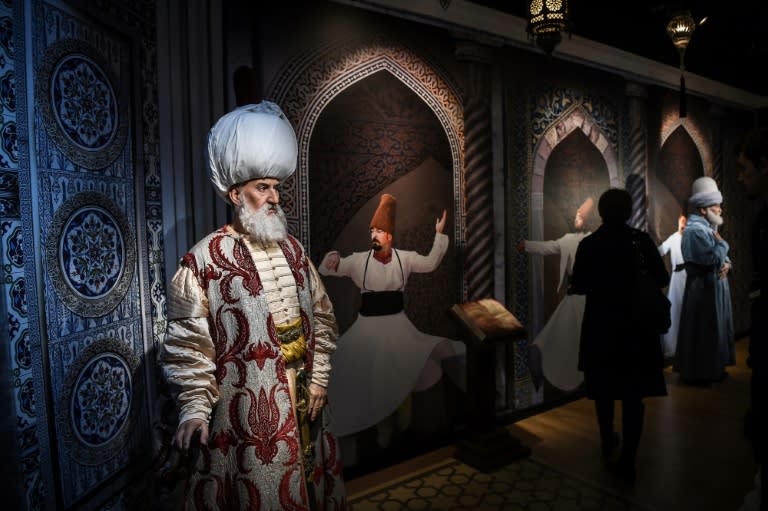 A visitor stands next to a wax statues of Ottoman ruler Suleiman the Magnificent (L) and of Persian poet Mevlana Jaladdin Rumi (R) at the world's 21st Madame Tussauds wax museum in Istanbul