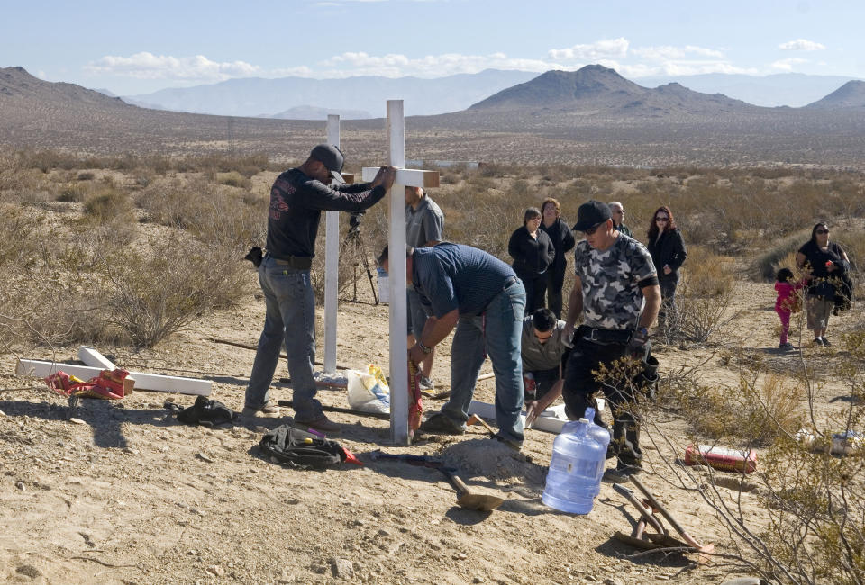 Photo showing residents of Victorville place crosses near the graves where the McStay family's remains were found. 