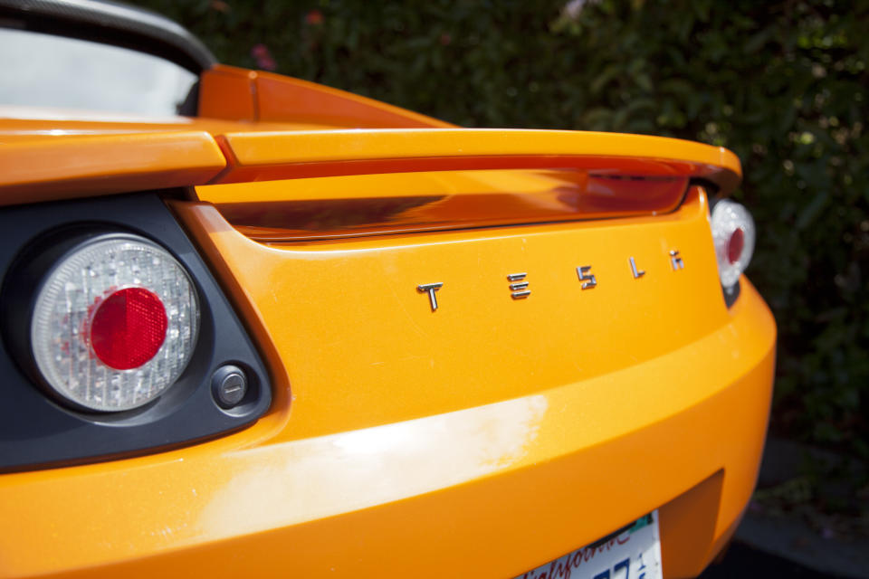 Palo Alto, California, USA - July 19, 2011: An exterior look at the rear end of an orange convertible Tesla Roadster electric sports car. The Roadster was designed in partnership with Lotus and debuted in 2008 and had a sticker price of around $100,000 dollars. Tesla plans to continue to sell the cars through 2012.