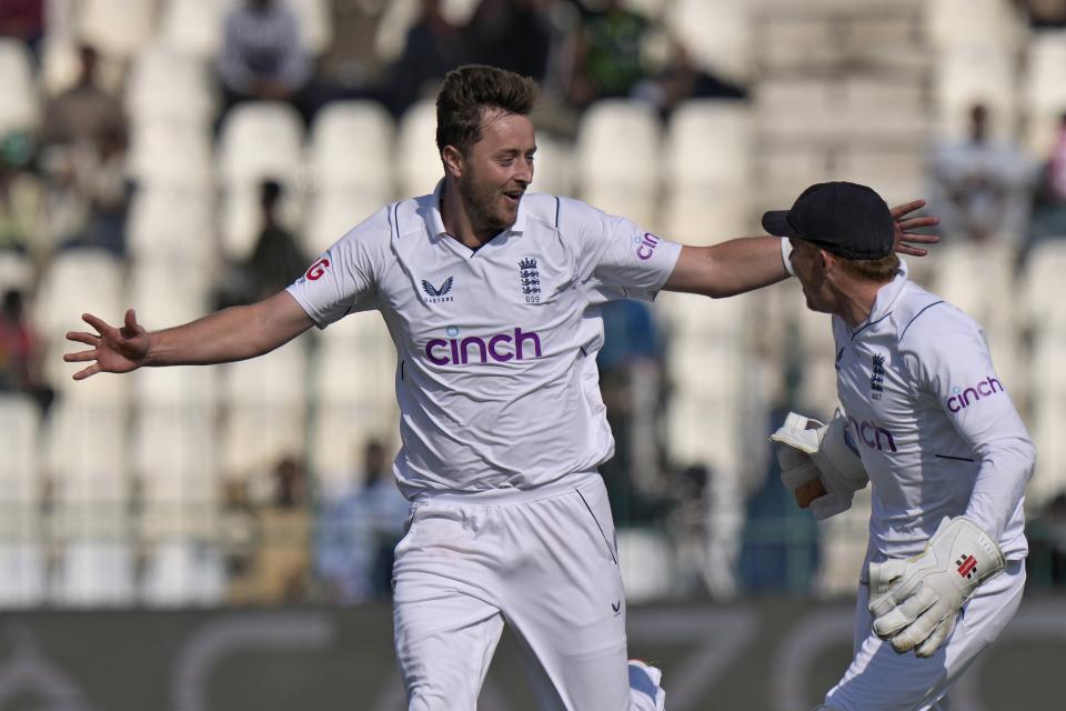 England's Ollie Robinson, left, celebrates with teammate after taking wicket of Pakistan's Babar Azam during the third day of the second test cricket match between Pakistan and England, in Multan, Pakistan, Sunday, Dec. 11, 2022. (AP Photo/Anjum Naveed)