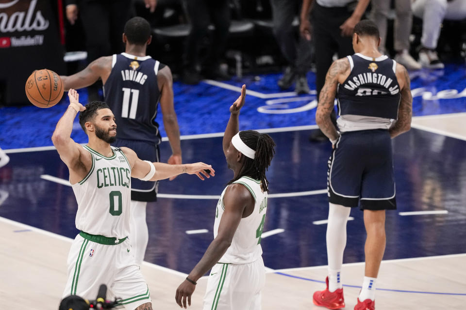 Boston Celtics forward Jayson Tatum (0) and guard Jrue Holiday react as Dallas Mavericks guard Kyrie Irving (11) and forward P.J. Washington walk off away after the Celtics won 109-66 in Game 3 of the NBA basketball finals, Wednesday, June 12, 2024, in Dallas. (AP Photo/Sam Hodde)