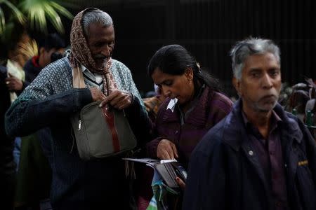 A woman checks her wallet as she stands in a queue outside the Reserve Bank of India (RBI) to exchange her old high denomination bank notes in New Delhi, India, December 30, 2016. REUTERS/Adnan Abidi