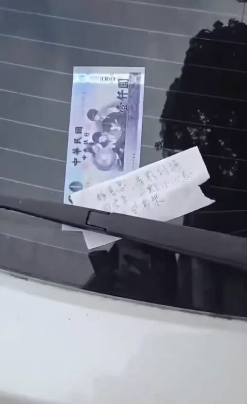 後擋風玻璃上夾著一張紙條和千元鈔。（圖／翻攝自爆廢公社）