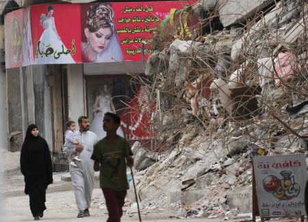 People walk past the rubble of damaged buildings in Raqqa, Syria October 12, 2018. REUTERS/Aboud Hamam