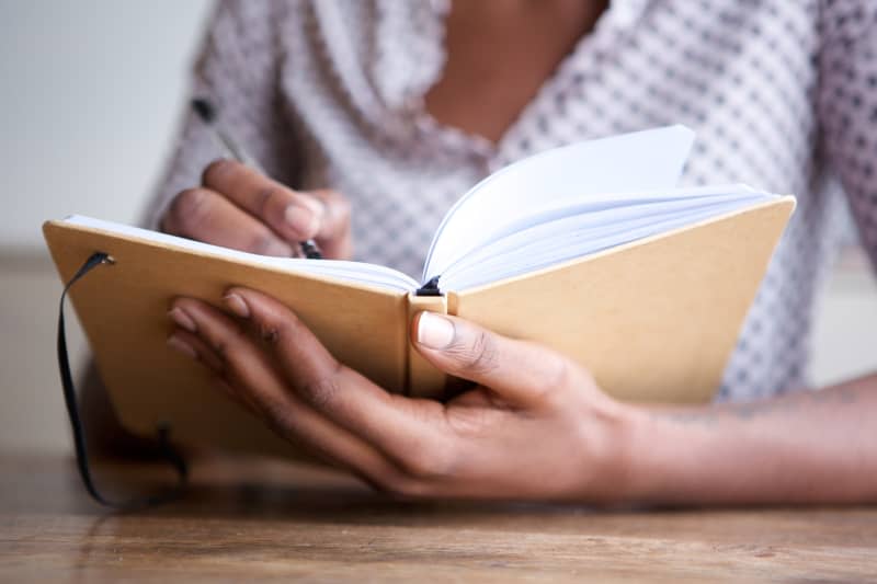 Close up of woman's hands writing in journal