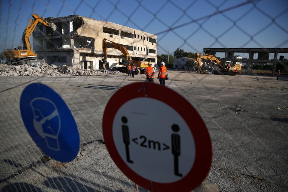 Bulldozers demolish an abandoned building at the old airport in Athens, Friday, July 3, 2020. Greece's Prime Minister Kyriakos Mitsotakis inaugurated the start of construction work on a long-delayed major development project at the prime seaside site of the old Athens airport. The development of the 620-hectare (1,500-acre) Hellenikon site was a key element of the privatization drive that was part of Greece's international bailouts. (AP Photo/Thanassis Stavrakis)