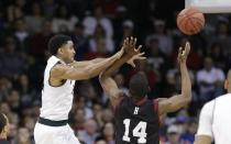 Michigan State's Gary Harris, left, passes as Harvard's Steve Moundou-Missi (14) defends in the first half during the third round of the NCAA men's college basketball tournament in Spokane, Wash., Saturday, March 22, 2014. (AP Photo/Elaine Thompson)
