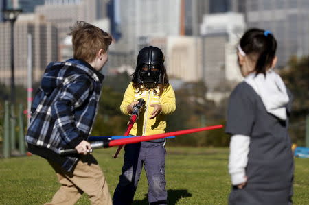 A child wearing a Darth Vader mask participates in a light saber duel with other children after the live internet unveiling of new light saber toys from the film "Star Wars - The Force Awakens" in Sydney, September 3, 2015. REUTERS/Jason Reed