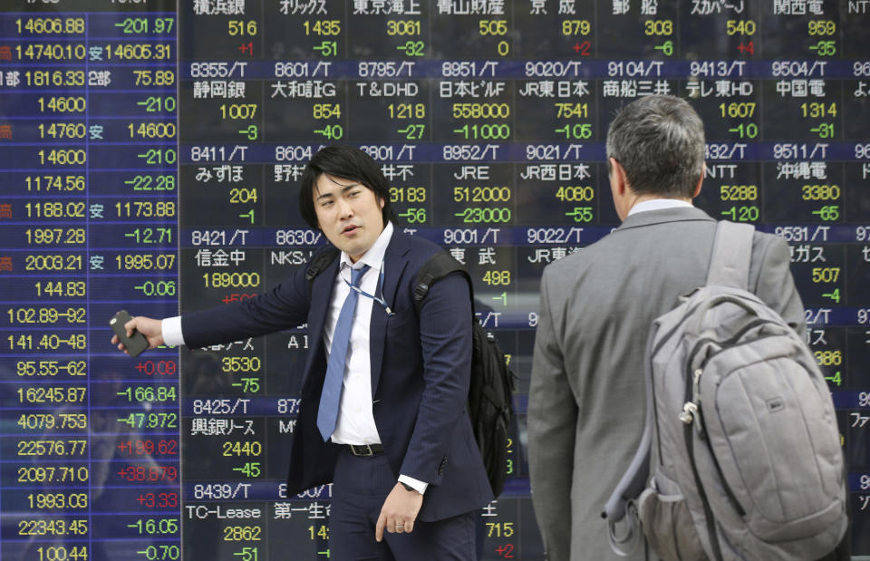 A man points at an electronic stock price indicator as he speaks with his colleague in Tokyo, Tuesday, April 8, 2014. Asian stock markets were mixed Tuesday after Japan's central bank refrained from expanding its stimulus and declines in tech stocks weighed on prices. The regional heavyweight, Tokyo's Nikkei 225, shed 201.97 points, or 1.36 percent to close at 14,606.88 after Japan's central bank refrained from expanding its ultra-loose monetary policy. (AP Photo/Eugene Hoshiko)