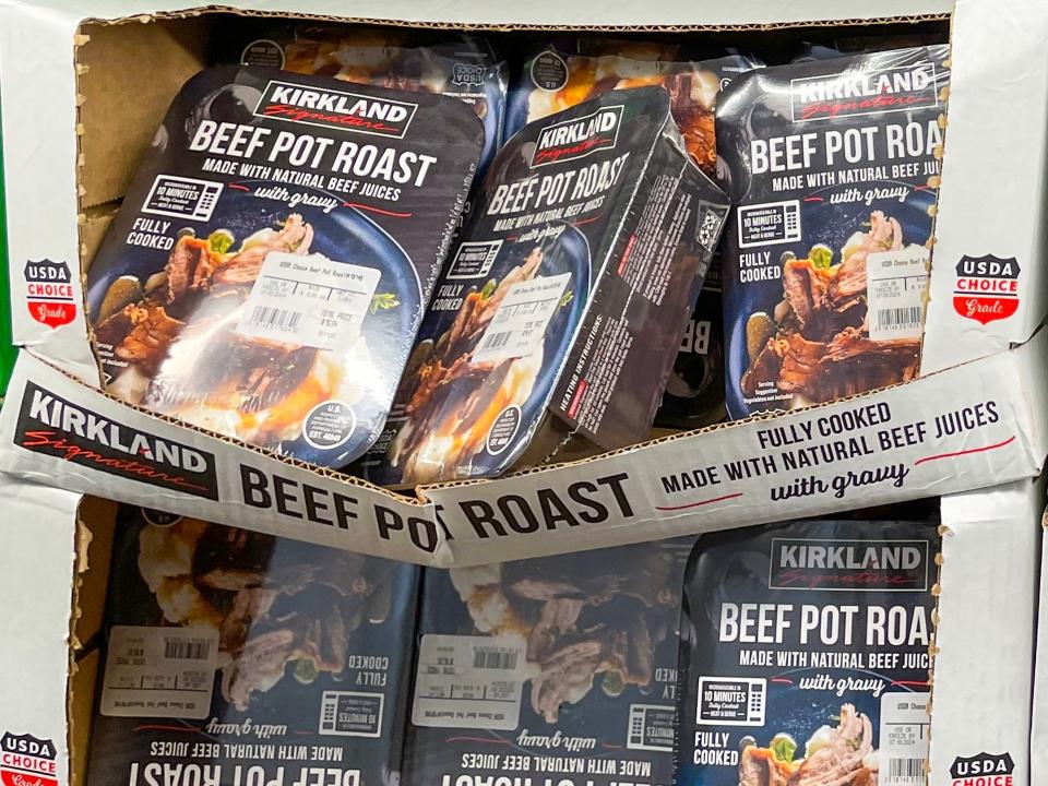 Several collapsing white cardboard boxes filled with black boxes with images of blue bowls with beef pot roasts on them