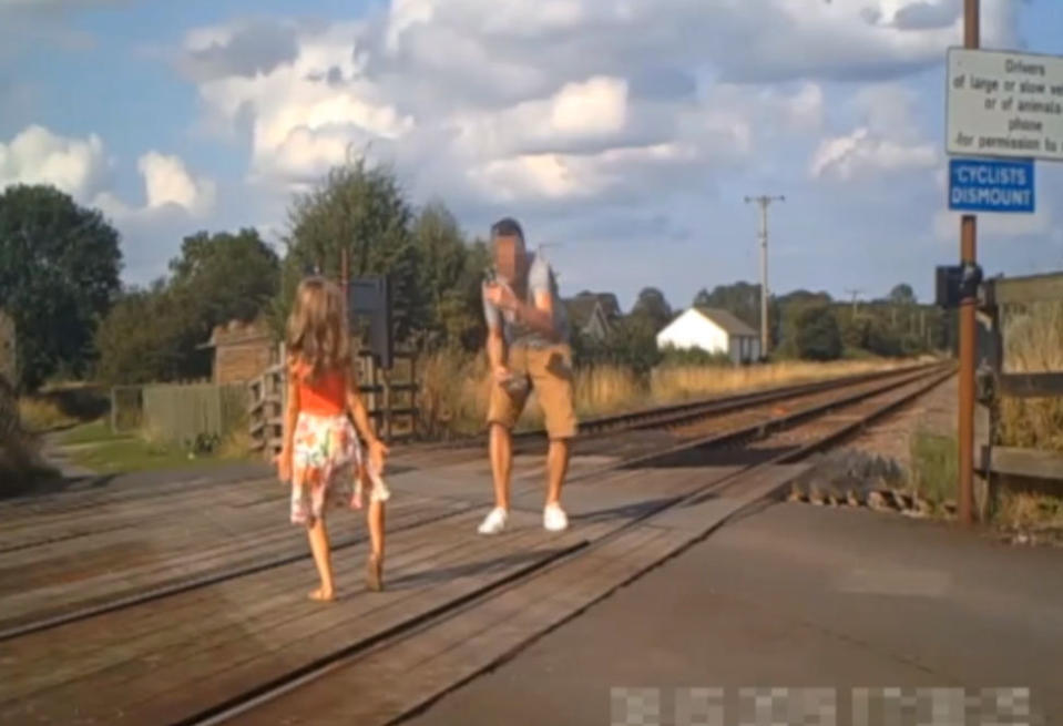 Shocking CCTV footage has been released which shows people risking their lives on level crossings - including a father and his young daughter posing for a photo shoot. The reckless father can be seen taking pictures of the little girl - who appears to be of primary school age - in different directions on the crossing. Their car can be seen in the background with its doors open as the youngster adopts various poses and occasionally looks behind her for approaching trains. Another shocking clip captured on CCTV shows a group of cyclists who dismount their bikes and line up for a group photo on the crossing.