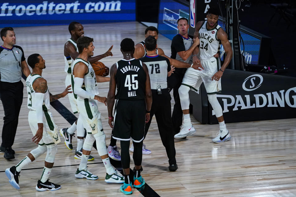 Referees separate players from the Milwaukee Bucks and Brooklyn Nets after a scuffle during the first half of an NBA basketball game Tuesday, Aug. 4, 2020 in Lake Buena Vista, Fla. (AP Photo/Ashley Landis)