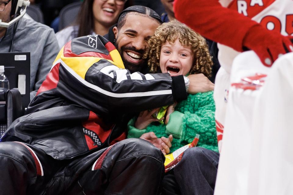 Drake embraces his son Adonis as the Raptor mascot brings over candy for him during the first half of the NBA game between the Toronto Raptors and the LA Clippers at Scotiabank Arena on December 27, 2022 in Toronto, Canada