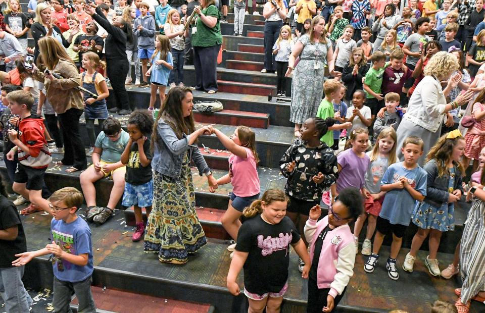 Kellie Martin, left, dances with second grade student Bella Thrift in the isle, as faculty and students celebrate to the Kool and the Gang dance classic "Celebration", in Anderson, S.C. April 23, 2024. North Pointe Elementary School was named as one of the 2023-24 Palmetto's Finest schools, during the announcement in the school auditorium.