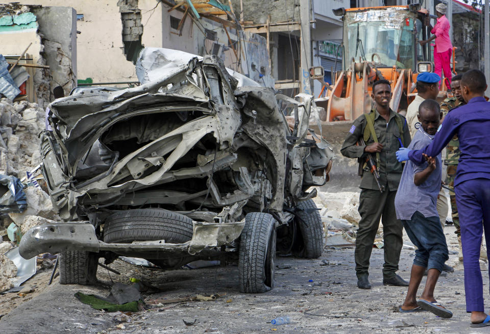 Security forces stand near the wreckage of an official vehicle that was destroyed in a bomb attack in the capital Mogadishu, Somalia Saturday, June 15, 2019. (AP Photo/Farah Abdi Warsameh)