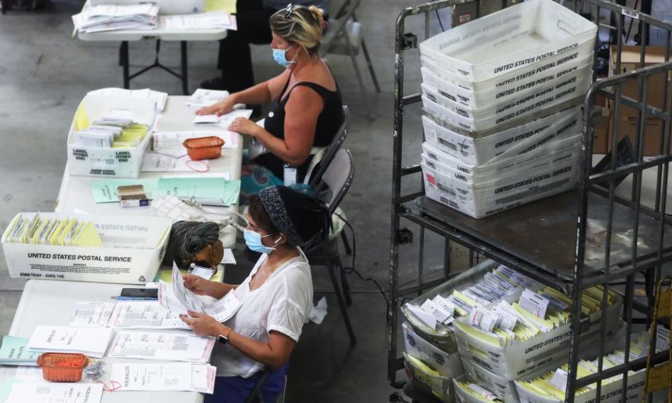 Election workers at the Orange county Registrar of Voters process stacks of mail-in ballots.