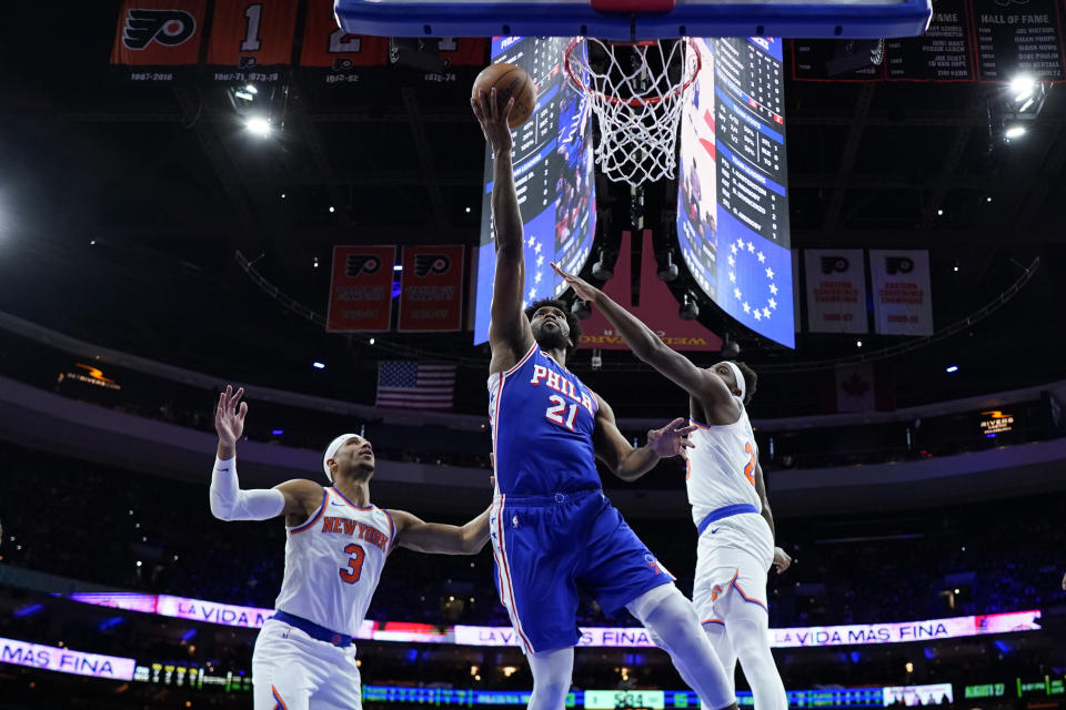 Philadelphia 76ers' Joel Embiid, center, goes up for a shot between New York Knicks' Mitchell Robinson, right, and Josh Hart during the first half of Game 3 in an NBA basketball first-round playoff series, Thursday, April 25, 2024, in Philadelphia. (AP Photo/Matt Slocum)