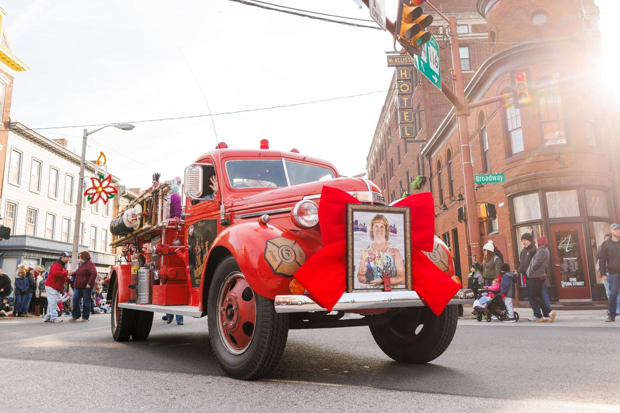 A vintage fire truck makes the turn onto Broadway with a sign honoring the parade's grand marshal, Andrea Goodson, during the Hanover Christmas Parade, Friday, Nov. 24, 2023, in downtown Hanover.