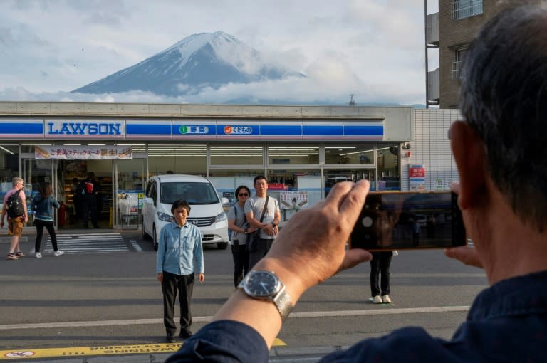 Tourists take pictures of Mount Fuji from opposite a convenience store in the town of Fujikawaguchiko, Yamanashi prefecture (Kazuhiro NOGI)
