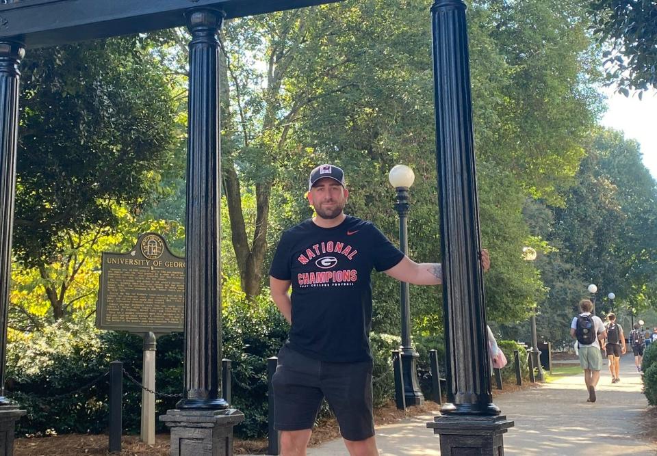 Chris Biggs stands at the famous UGA Arch at the corner of campus and downtown Athens.