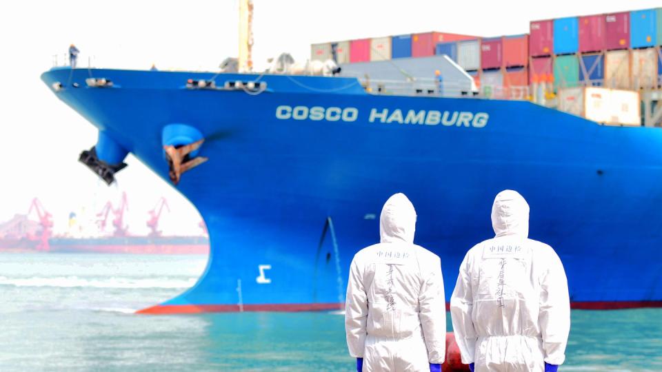 Zwei Hafenmitarbeiter in Qingdao beobachten den Containerfrachter «Cosco Hamburg».