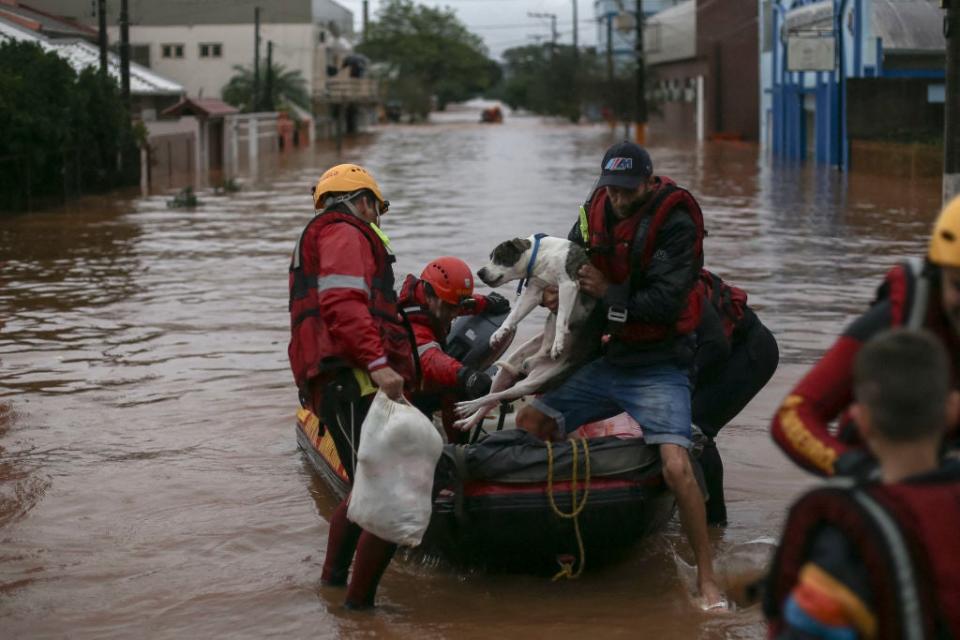 Firefighters rescue a man and his dog from a flooded area at the city center of Sao Sebastiao do Cai, Rio Grande do Sul state, Brazil on May 2, 2024.