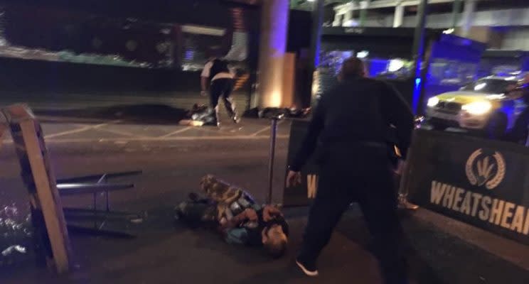 A photo showing what is thought to be two suspected terrorists with cannisters reportedly strapped to their bodies with police officers standing over them (Gabriele Sciotto/Instagram)