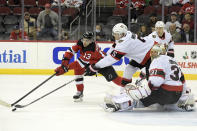 New Jersey Devils center Nico Hischier (13) reaches for the puck with Ottawa Senators defenseman Nick Holden (5) as Senators goaltender Anton Forsberg (31) looks on during the first period of an NHL hockey game Monday, Dec. 6, 2021, in Newark, N.J. (AP Photo/Bill Kostroun)