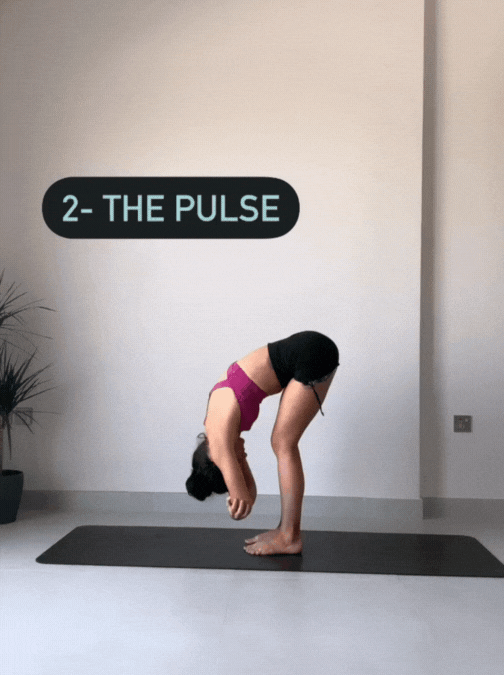 Woman standing on her yoga mat in Uttanasana making pulsing movements with her spine to relax her thoracic and cervical vertebrae