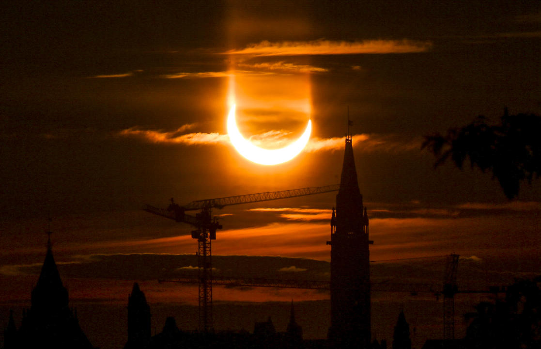 An annular solar eclipse rises over construction cranes and the Peace Tower on Parliament Hill in Ottawa on Thursday, June 10, 2021. THE CANADIAN PRESS/Sean Kilpatrick