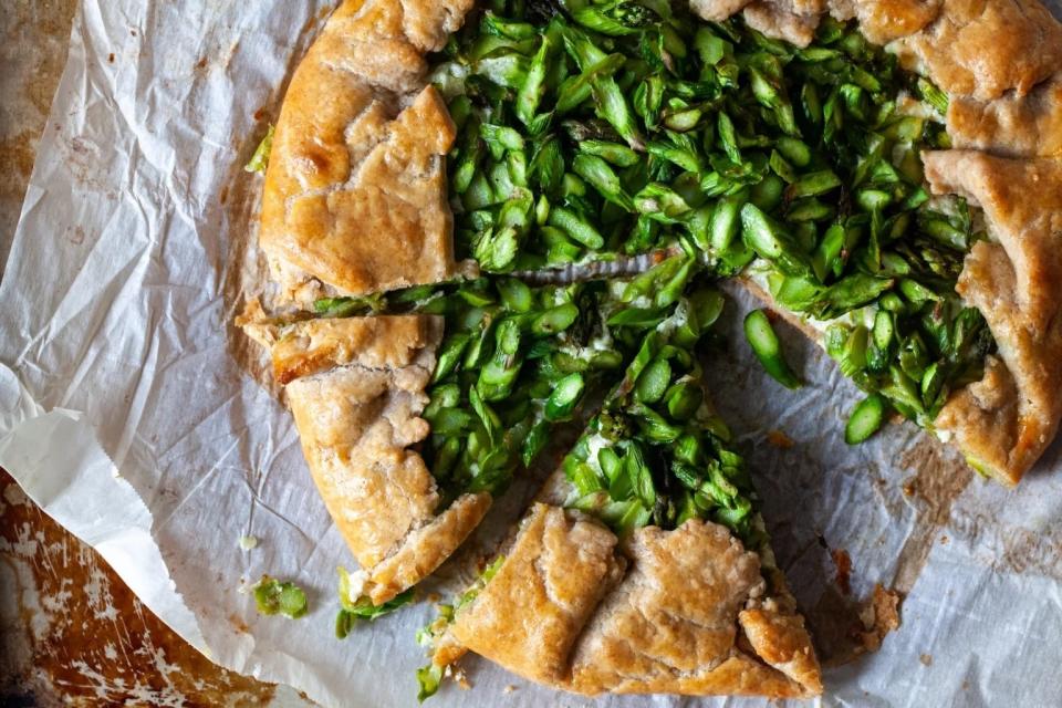 asparagus galette with a slice taken out, on parchment paper