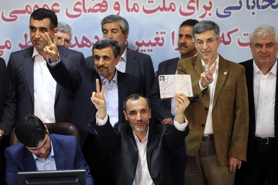 Former Iranian President Mahmoud Ahmadinejad, second left, and his close allies Hamid Baghaei, center, Esfandiar Rahim Mashei, second right, flash the victory sign as Baghaei shows his identification while registering candidacy of Ahmadinejad and Baghaei for the upcoming presidential elections at the Interior Ministry in Tehran, Iran, Wednesday, April 12, 2017. Ahmadinejad on Wednesday unexpectedly filed to run in the country's May presidential election, contradicting a recommendation from the supreme leader to stay out of the race. (AP Photo/Ebrahim Noroozi)