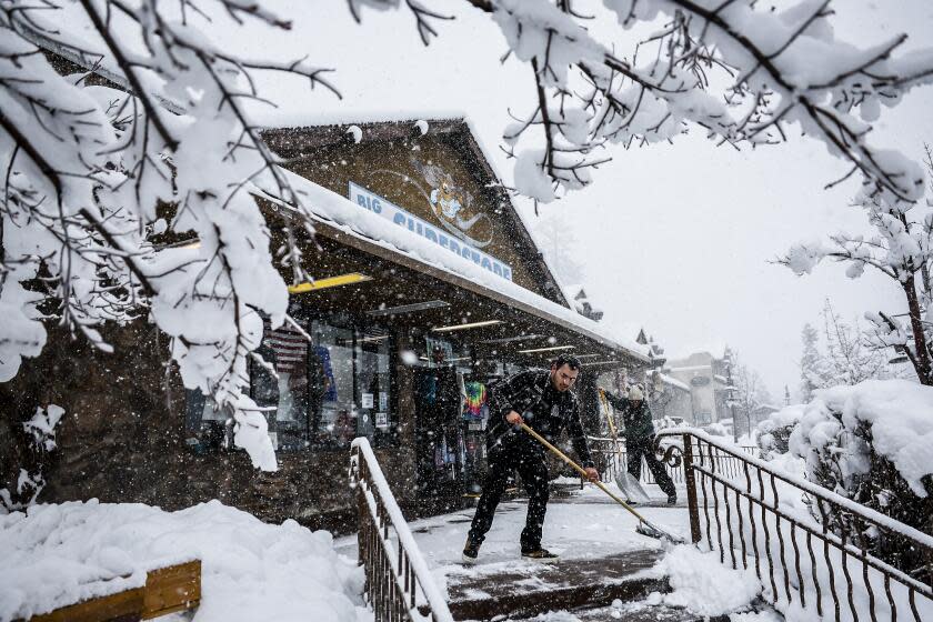 Big Bear, CA, Tuesday, February 6, 2024 - Brayan Arreola (cq) and Cynthia Ramirez clear snow from the porch of Big Bear Superstore as a snowstorm blankets Big Bear. (Robert Gauthier/Los Angeles Times)