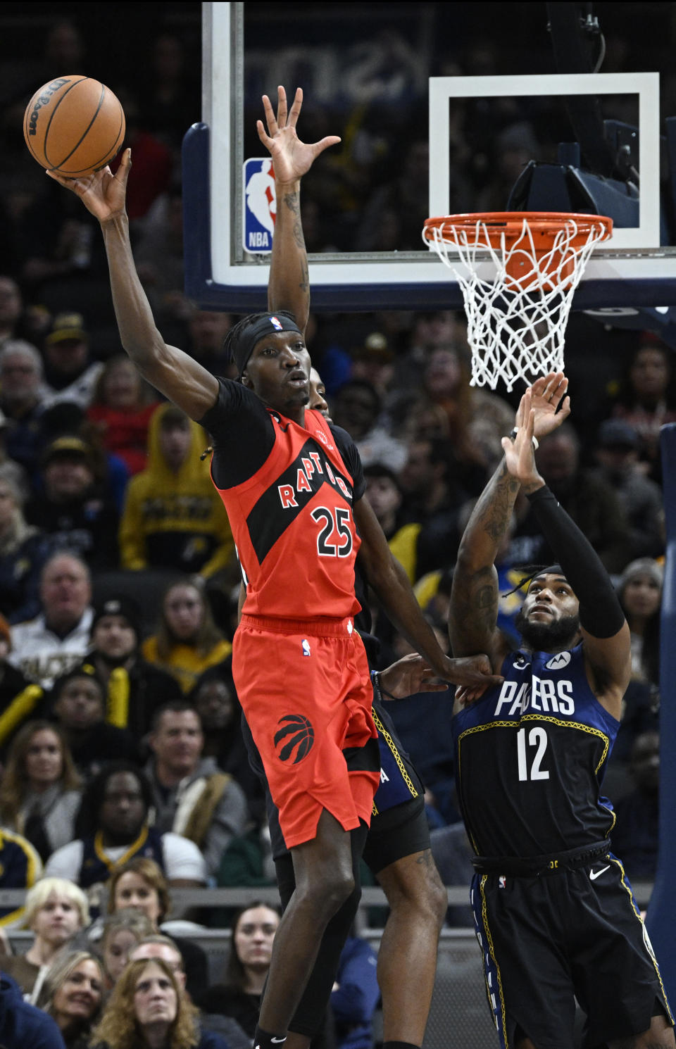 Toronto Raptors forward Chris Boucher (25) passes the ball away from Indiana Pacers forward Oshae Brissett (12) during the second half of an NBA basketball game, Saturday, Nov. 12, 2022, in Indianapolis, Ind. (AP Photo/Marc Lebryk)