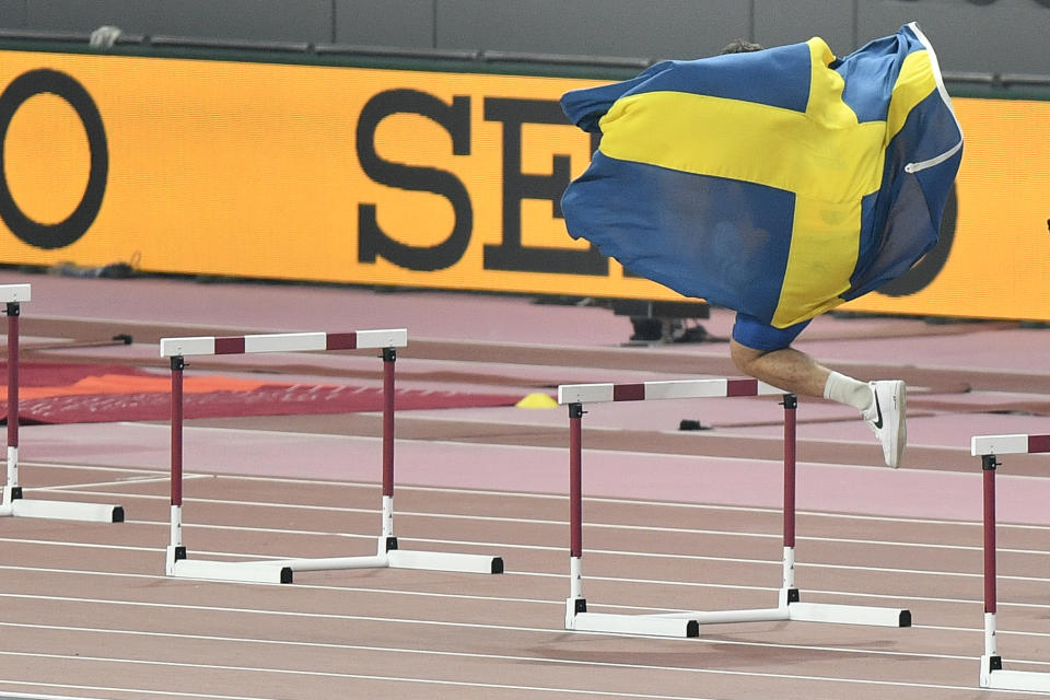 Daniel Ståhl, of Sweden, celebrates jumping over hurdles after winning the gold medal in the men's discus throw final during the World Athletics Championships in Doha, Qatar, Monday, Sept. 30, 2019. (AP Photo/Martin Meissner)