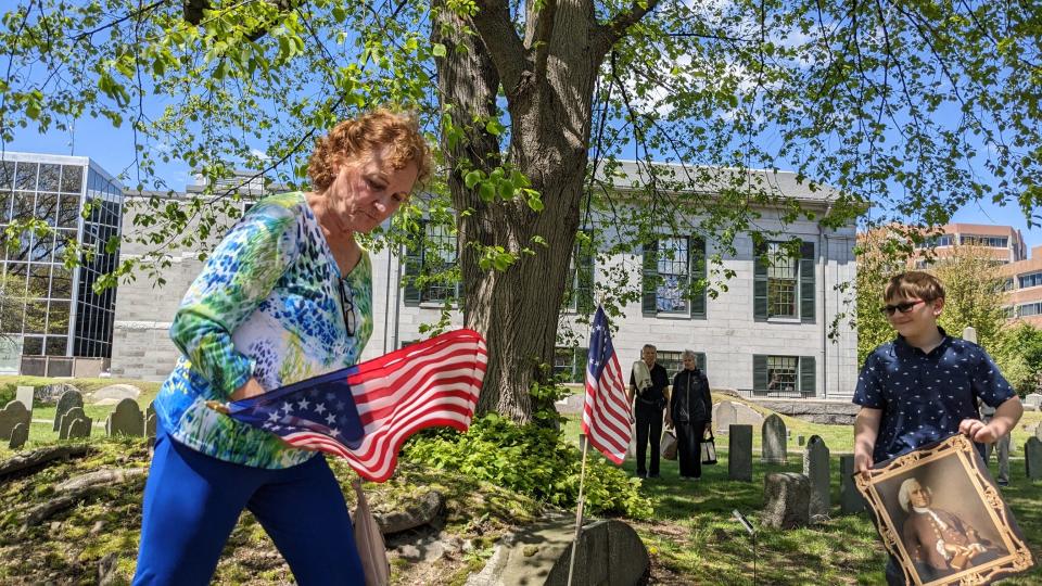 Author Janet Ulhar places flags at the grave of Col. Josiah Quincy after outlining his contributions to American independence from Great Britain Sunday, May 7, 2023.