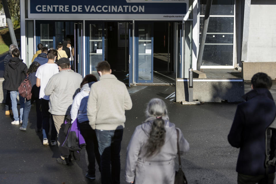 People wait in line outside a vaccination center, in Nantes, western France, Thursday, Dec. 30, 2021. France has vaccinated 77% of its population and is rushing out booster shots. But more than 4 million adults remain unvaccinated. (AP Photo/Jeremias Gonzales)