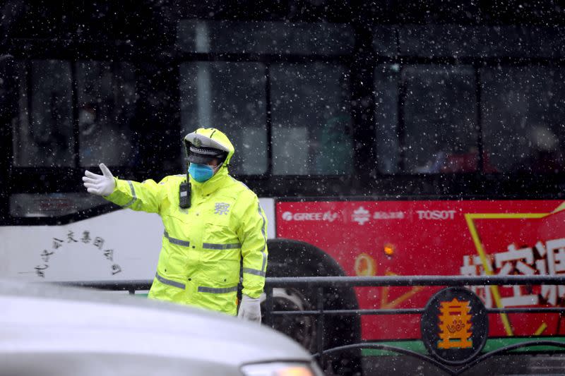 Police officer directs the traffic amid snowfall in Wuhan, the epicentre of the novel coronavirus outbreak