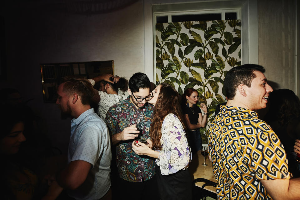 Group of people socializing at an indoor event, one focused pair in conversation