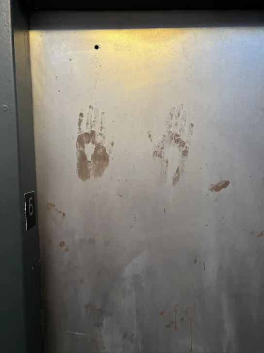 Handprints on a metallic elevator wall, seen on floor 6