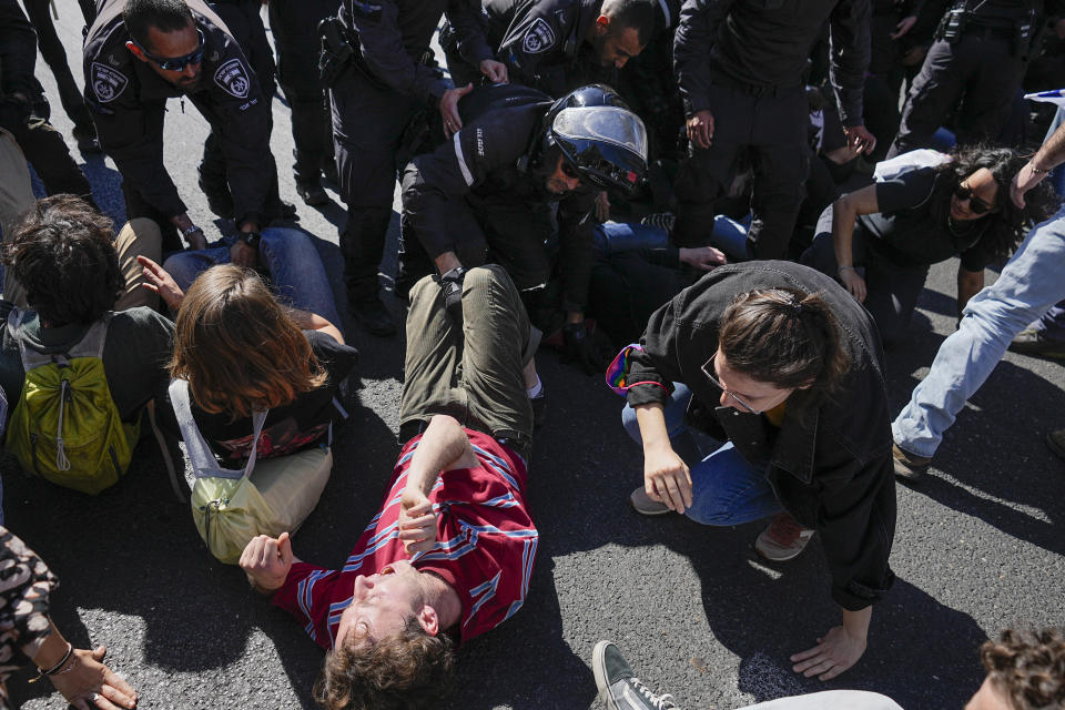 Police officers scuffle with demonstrators as they block a highway during protest against plans by Prime Minister Benjamin Netanyahu's government to overhaul the judicial system, in Tel Aviv, Israel, Thursday, March 9, 2023. (AP Photo/Ohad Zwigenberg)