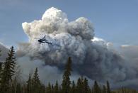 A helicopter flies past a wildfire in Fort McMurray, Alta., on Wednesday May 4, 2016. THE CANADIAN PRESS/Jason Franson