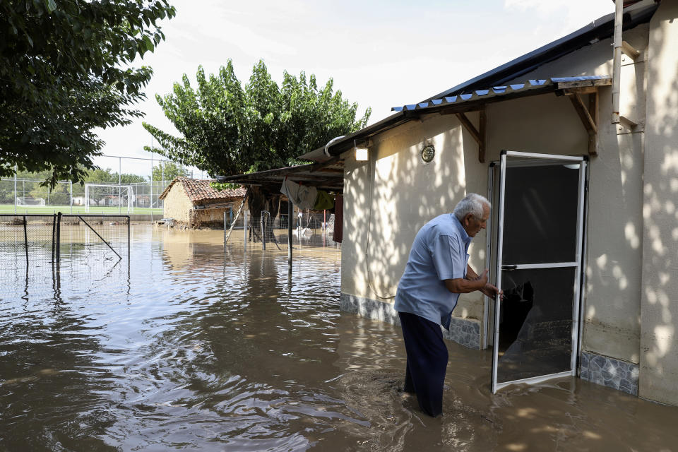 A man tries to enter his flooded home at Magoula village, near Karditsa town, Saturday, Sept. 19, 2020. Two people have died and one is reported missing in the central Greek region of Thessaly as a rainstorm pounded parts of central and western Greece overninght and caused rivers to burst their banks and flood surrounding areas. (AP Photo/Vaggelis Kousioras)