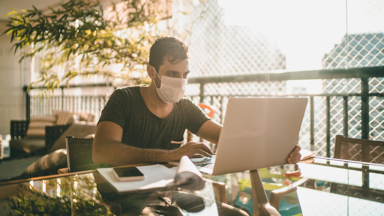 guy with face mask sending payment laptop