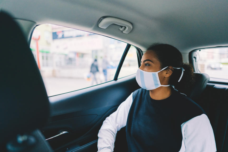 Mixed race woman with protective face mask travel by taxi