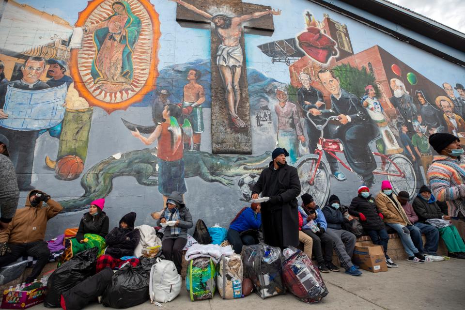 Migrants eat and wait for help while camping on a street in downtown El Paso, Texas, Sunday, Dec. 18, 2022.