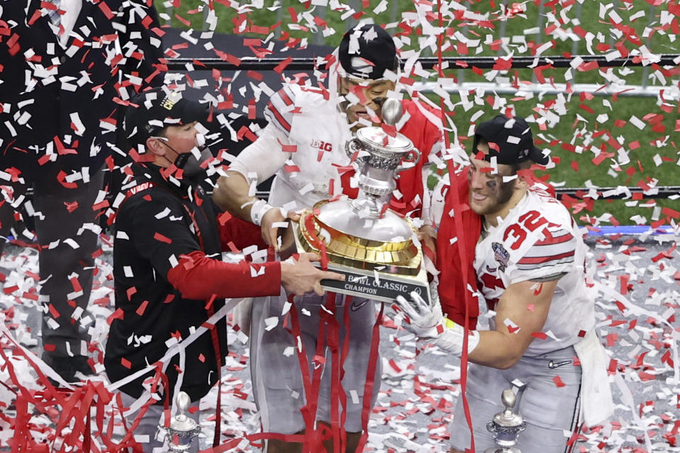 Ohio State head coach Ryan Day, from left, quarterback Justin Fields and linebacker Tuf Borland hold up the trophy after their win against Clemson in the Sugar Bowl NCAA college football game Friday, Jan. 1, 2021, in New Orleans. Ohio State won 49-28. (AP Photo/Butch Dill)