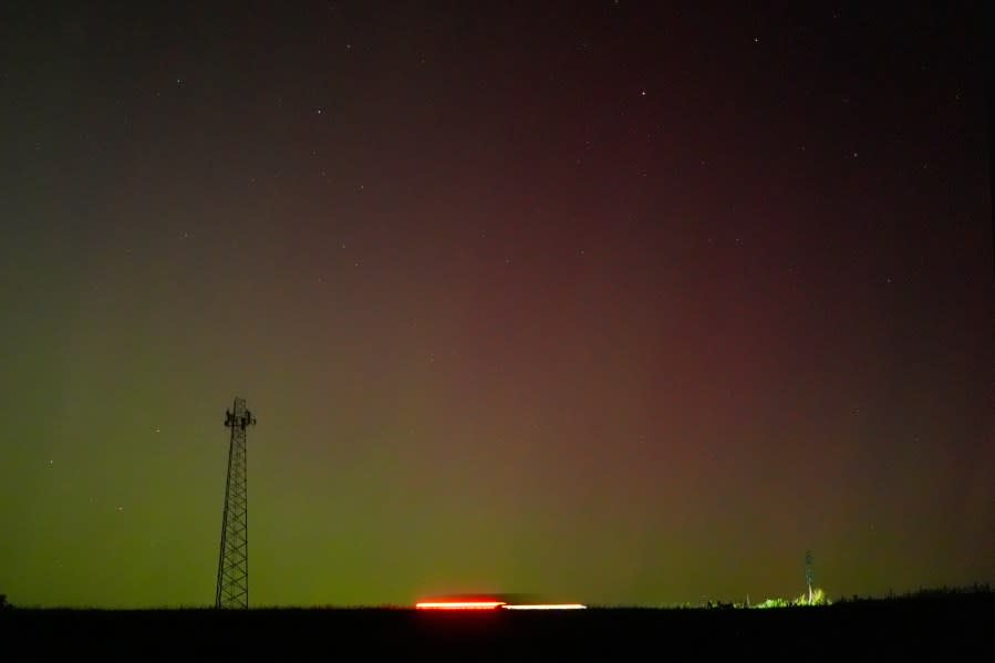 A communications tower is silhouetted against the northern lights Saturday, May 11, 2024, near St. Joseph, Mo. (AP Photo/Charlie Riedel)