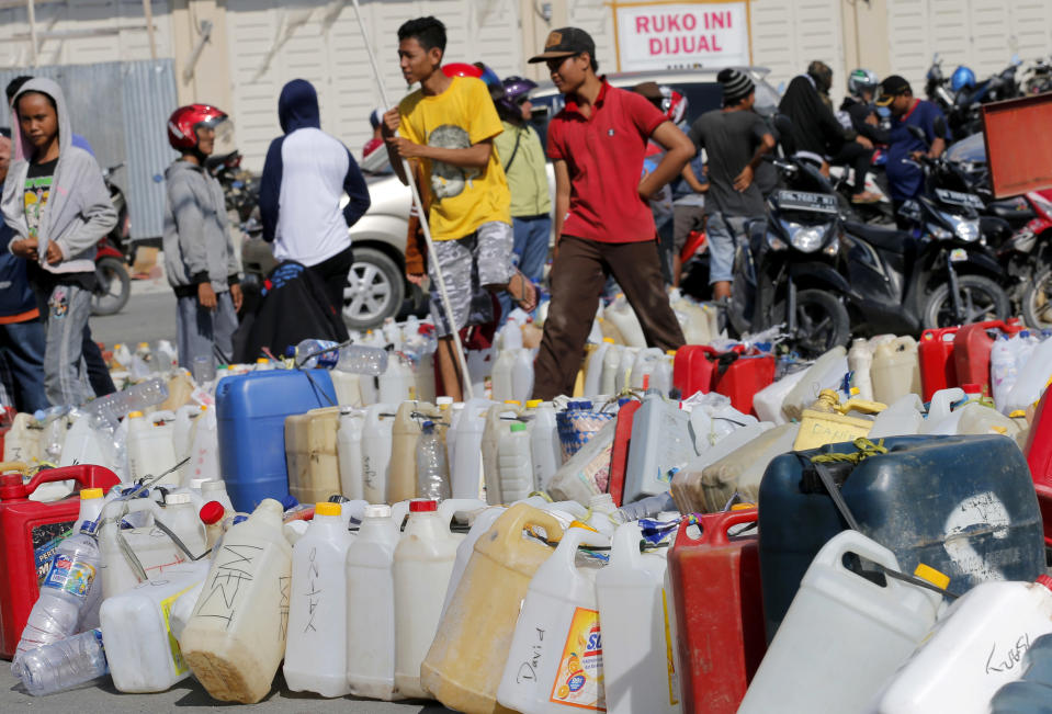 People queue for gasoline following a massive earthquake and tsunami at a gas station in Palu, Central Sulawesi, Indonesia, Monday, Oct. 1, 2018. A mass burial of earthquake and tsunami victims was being prepared in a hard-hit city Monday as the need for heavy equipment to dig for survivors of the disaster that struck a central Indonesian island three days ago grows desperate. (AP Photo/Tatan Syuflana)