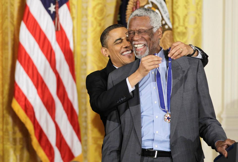 President Barack Obama reaches up to present a 2010 Presidential Medal of Freedom to Basketball Hall of Fame member, former Boston Celtics coach and captain Bill Russell, Tuesday, Feb. 15, 2011, during a ceremony in the East Room of the White House in Washington.